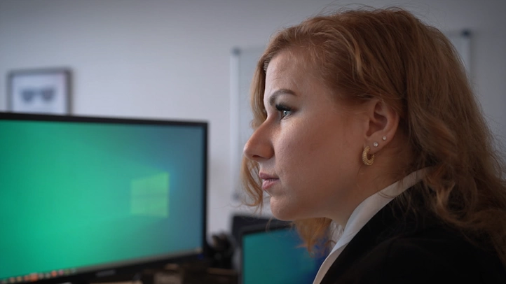 Eine Frau schaut konzentriert bei der Arbeit auf einen Bildschirm.