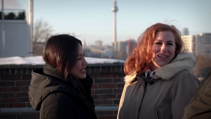 Zwei Kolleginnen unterhalten sich auf der Dachterrasse. Im Hintergrund ist der Berliner Fernsehturm zu sehen.
