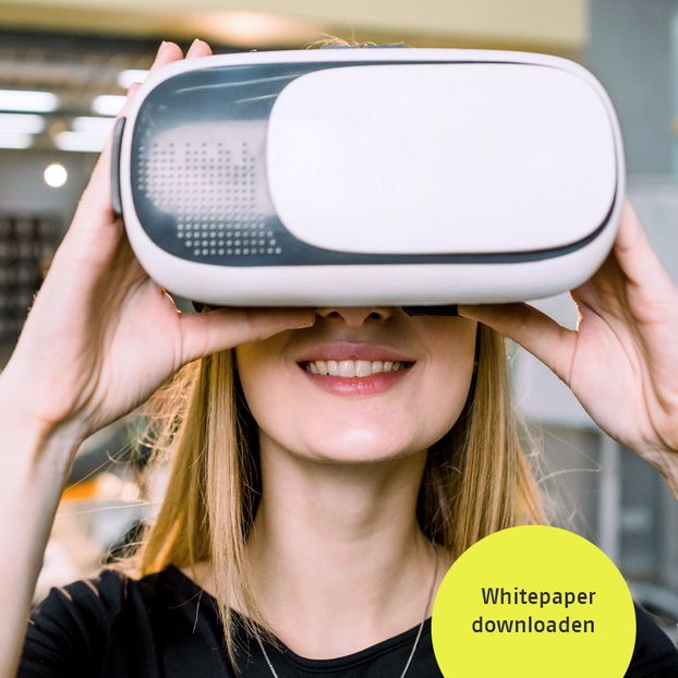 Eine junge Frau hält ein Virtual Reality Headset vor ihr Gesicht.