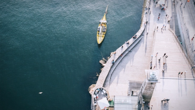 Aerial view of a white ship next to a yellow boat by day