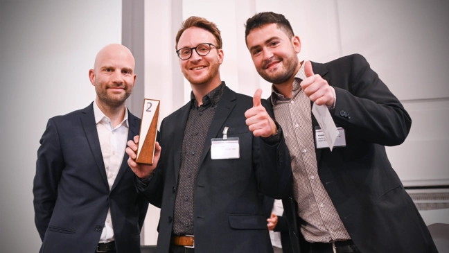 Tim Kirlicks (]init[ AG) zeichnet Felix Bauch und Konstantin Moser (Martin-Luther-Universität Halle-Wittenberg) mit dem Innovationspreis Medizinische Register (2. Platz) für BeoNet-Halle aus. Foto: Volkmar Otto