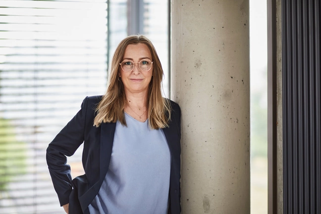 Sandra Valentin, Chief Operating Chief Operating Officer of ]init[ AG, leans against a concrete pillar in her office in Berlin.