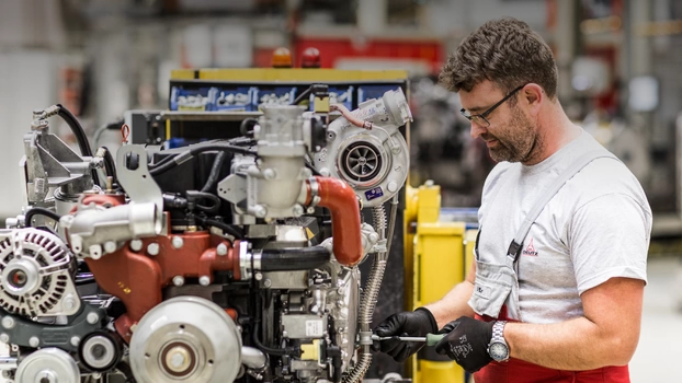 Ein Mitarbeiter der Deutz AG repariert in einer Fertigungshalle einen Industriemotor.