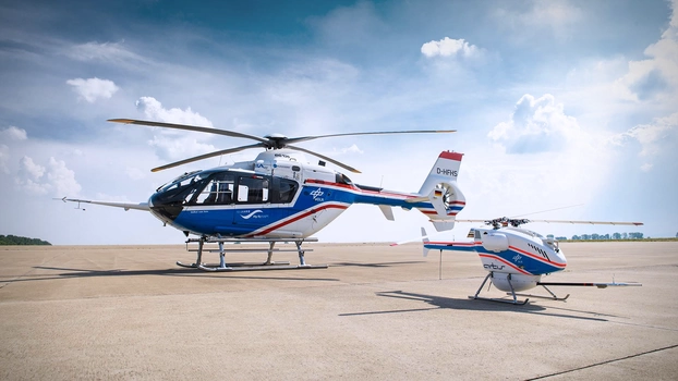 A DLR helicopter and drone on an airfield on the ground.