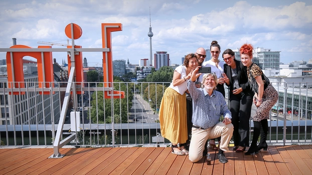Ein UX-Team macht nach Abschluss eines Workshops gemeinsam mit den Teilnehmenden ein Erinnerungsfoto auf der Dachterrasse des Berliner Standortes. Im Hintergrund sind der Fernsehturm und Ostbahnhof zu erkennen.