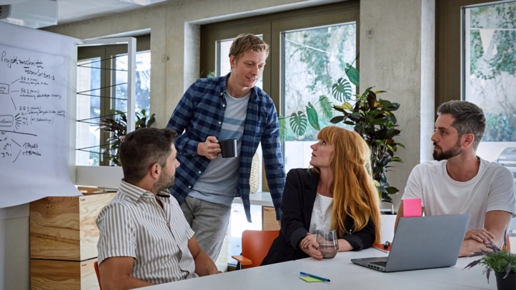 Ein Projektteam berät sich in einem großen Besprechungsraum.