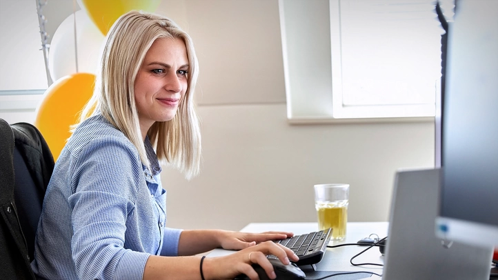 A colleague at the Leipzig site works on her PC. Balloons can be seen in the background.