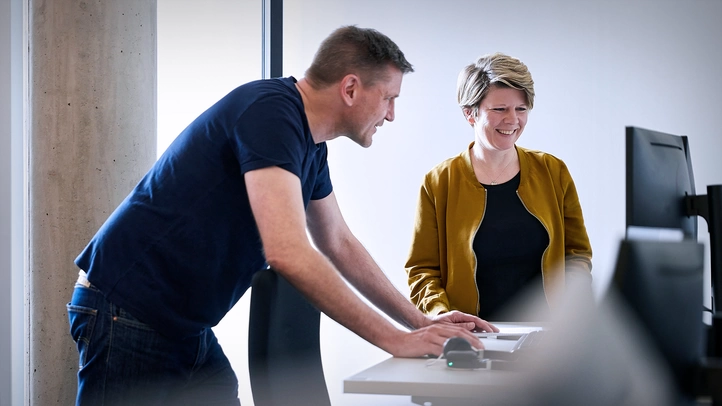 Ein Mitarbeiterin und eine Mitarbeiter diskutieren am Bildschirm.