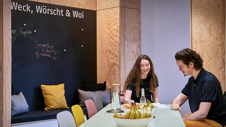 An employee and a co-worker chat while seated in one of the modern kitchen and lounge areas at the Mainz location.