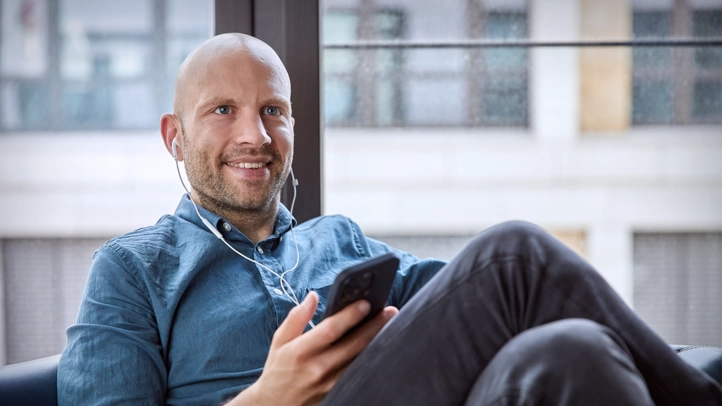 An employee sits comfortably in an armchair and talks on the phone with a headset.