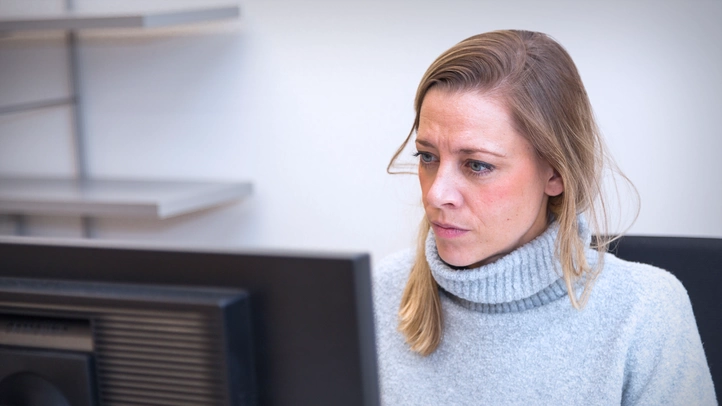 Eine Mitarbeitern am München Standort arbeitet konzentriert vor einem Monitor.