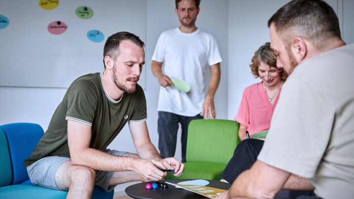 Drei Männer und eine Frau arbeiten in einem Kreativraum an einem Lösungskonzept. Dafür nutzen sie verschiedene Kreativmethoden.