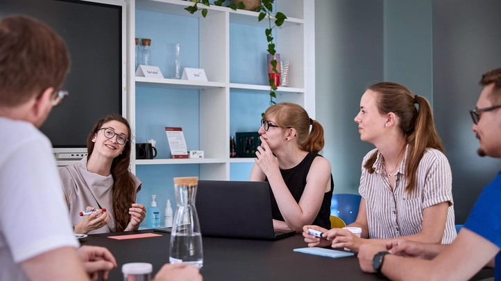 Ein Projektteam hört aufmerksam einer Projektleiterin zu.