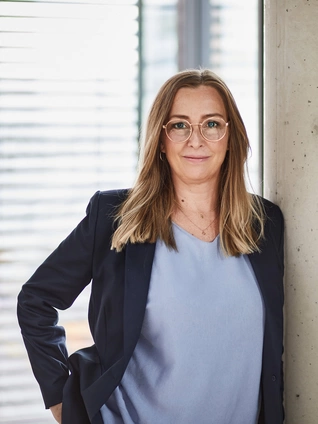 Sandra Valentin, Chief Operating Chief Operating Officer of ]init[ AG, leans against a concrete pillar in her office in Berlin.