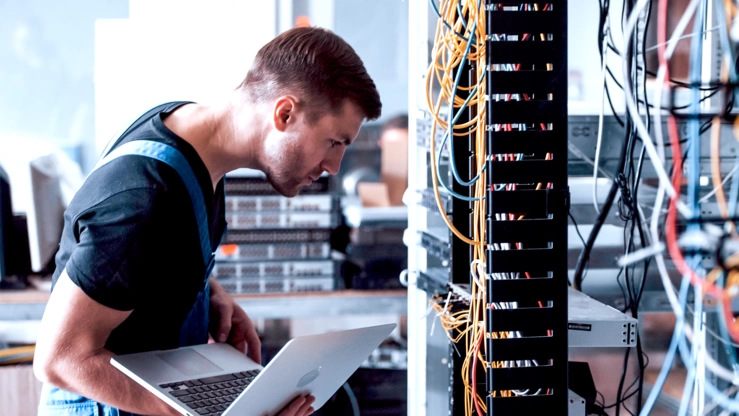 Ein Systemadministrator arbeitet in einem Rechenzentrum an einem Serverschrank.