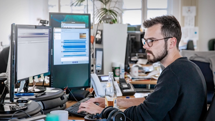 A system engineer working intently in front of two screens. 