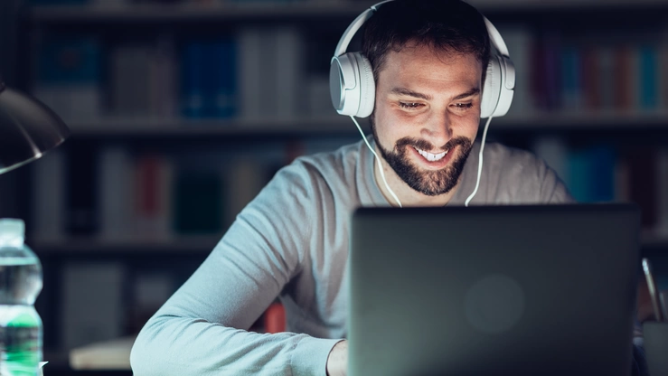 Eine Person arbeitet abends konzentriert am Laptop.