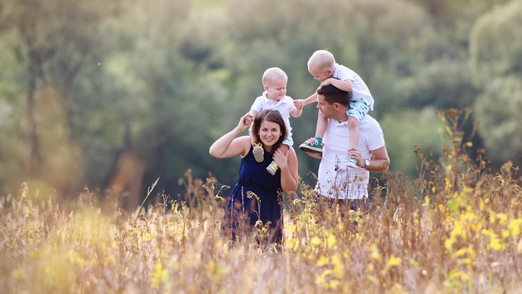 Eine Familie mit zwei Kleinkindern spaziert über eine Wildblumenwiese.