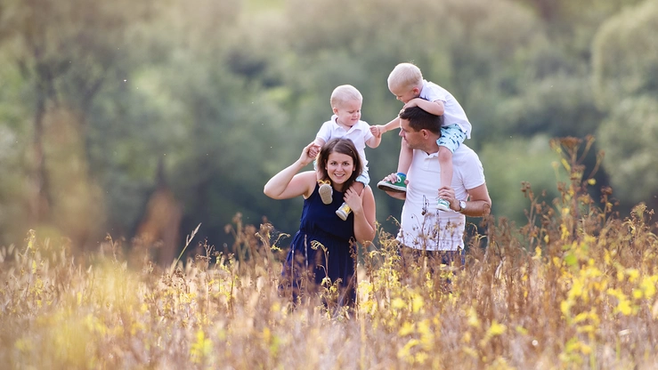 A family with two small children walks across a wildflower meadow.