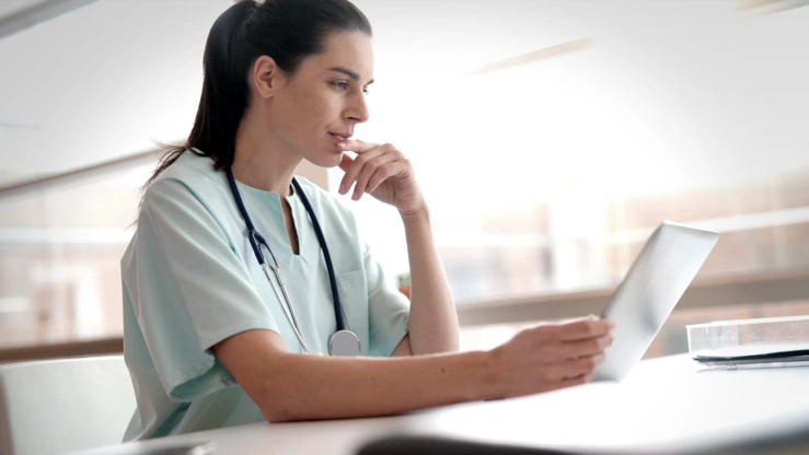 Eine Ärztin schaut sich konzentriert Gesundheitsdaten auf einem Tablet an. 