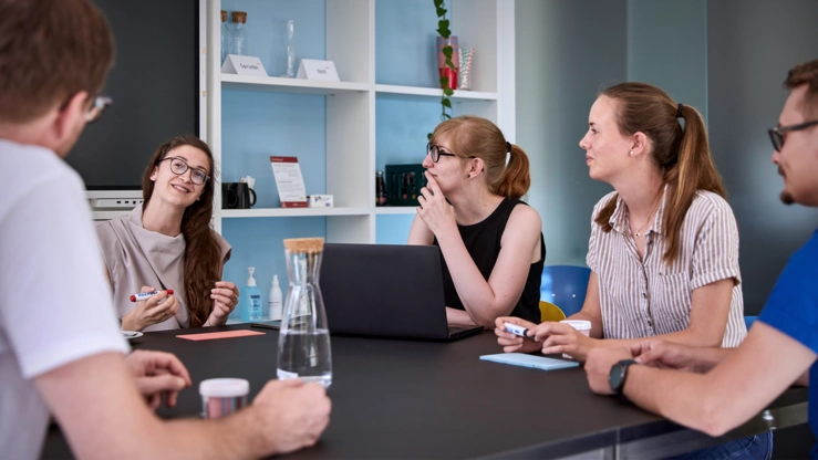 Ein Projektteam berät sich im Besprechungsraum.