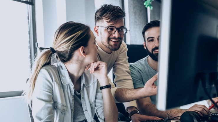 Drei Personen diskutieren vor einem PC.