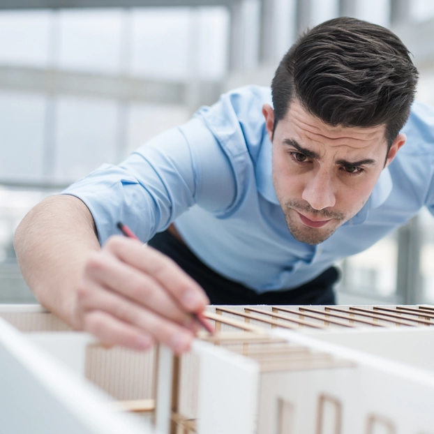 Ein Architekt stellt das Mockup eines Gebäudes fertig.