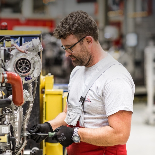 A Deutz AG employee repairs an industrial engine in a production hall.