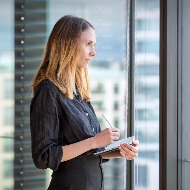 Eine Frau vor einer Glasscheibe mit Ausblick über Berlin
