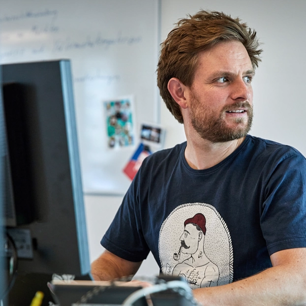 Person arbeitet am PC-Arbeitsplatz in einer Agentur
