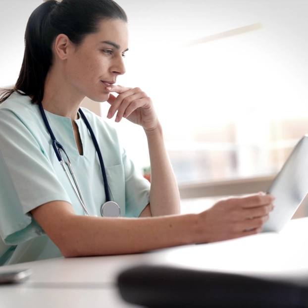 Eine Ärztin schaut sich konzentriert Gesundheitsdaten auf einem Tablet an. 