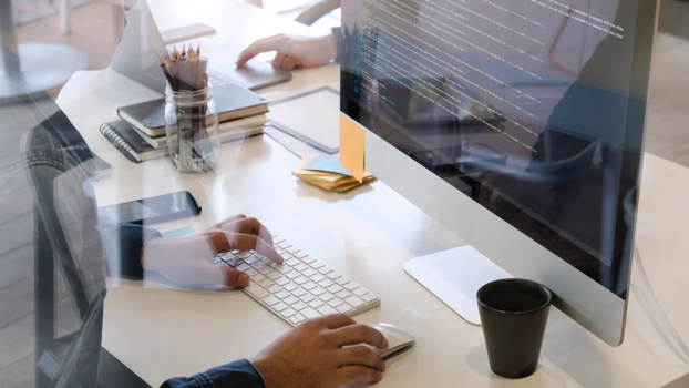 At a desk, a developer works on the code of a CMS platform.