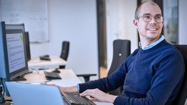 Glücklicher Mann vor seinem Arbeitsplatz