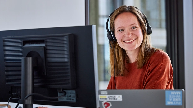 Glückliche Mitarbeiterin vor Bildschirm