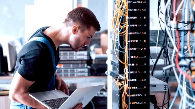 Ein Systemadministrator arbeitet in einem Rechenzentrum an einem Serverschrank.