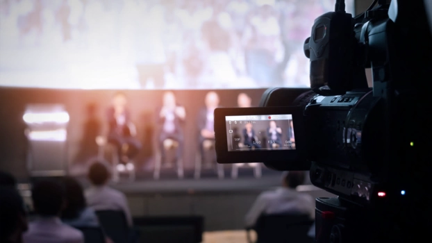 A camera with preview display films a panel discussion.