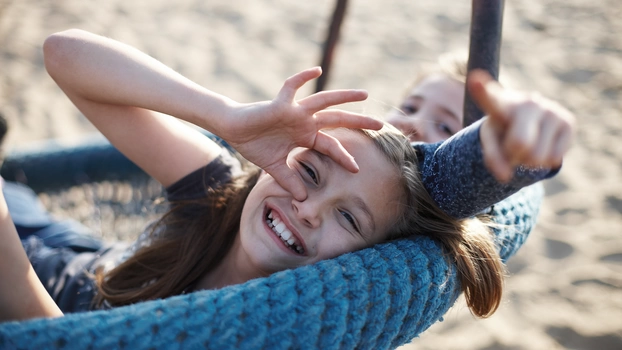 Two girls are sitting on a swing.