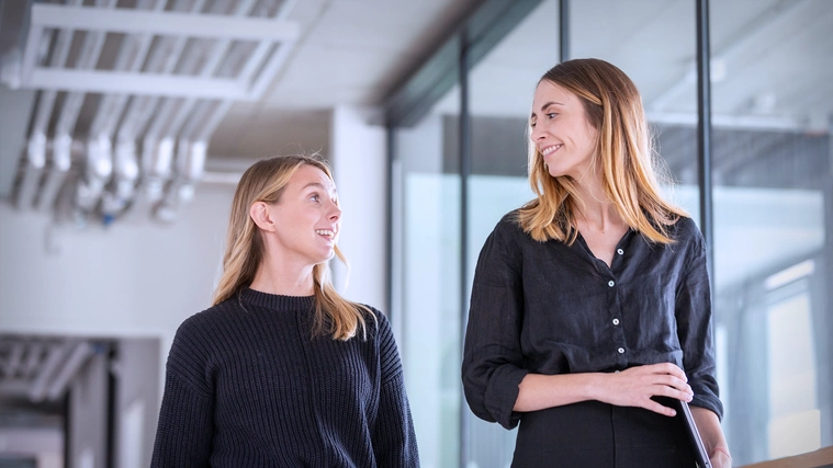 UX Designerin Nicole Lössner läuft mit einer Kollegin durch einen Gang im Berliner Office.